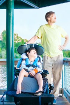 Caucasian father enjoying the lake with disabled ten year old son in wheelchair together
