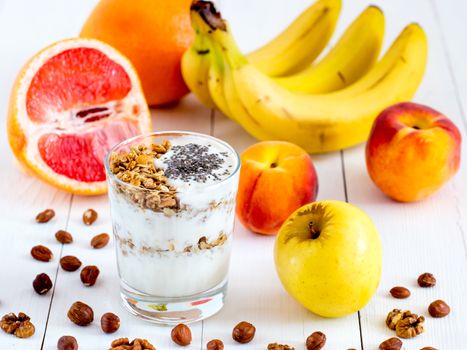 Healthy breakfast: yogurt with muesli and chia seeds, fruits and nuts on white wooden background. Dieting, healthy lifestyle concept meal