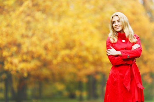 Young woman in red coat walking in autumn park