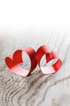 Two red small ribbon hearts on wooden background