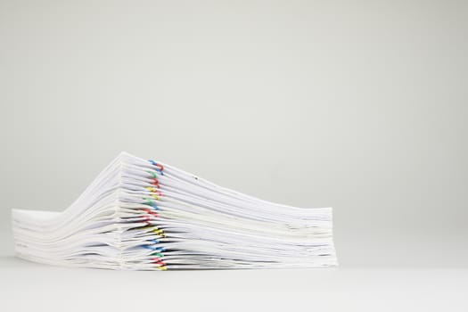 Pile overload of paper with colorful paper clip place on white background.