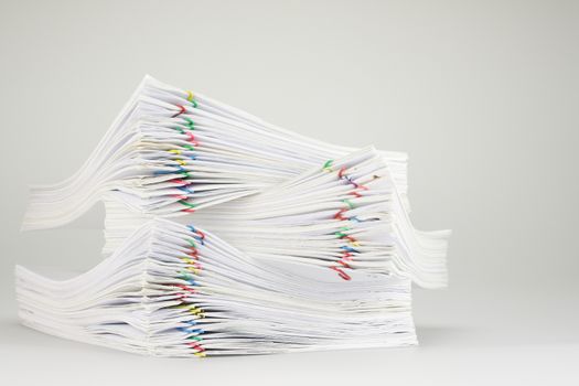 Pile overload of paperwork with colorful paper clip place on white table.