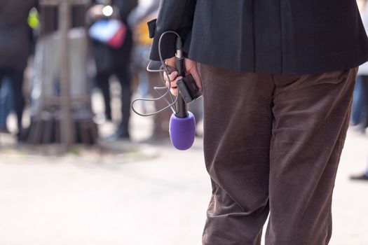 Journalist holding a microphone, waiting for an interview 