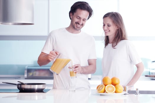 Couple with orange juice in the kitchen