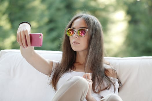 Beautiful young girl with smartphone sitting outdoors