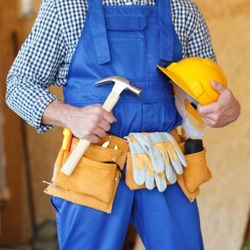 Construction worker with hammer in hand and tools at construction site