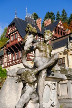Statue in front of beautiful Peles castle and ornamental garden in Sinaia, Romania, between Valachia and Transylvania