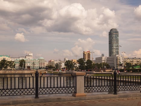 Embankment of the river Iset.House of Sevastyanov and Vysotsky skyscraper in the background. Yekaterinburg city.Day. Cloudy. Sverdlovsk region. Russia.