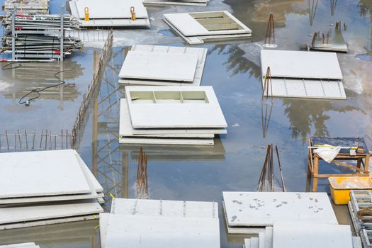 View of a flooded deep construction site with steel and precast concrete walls.