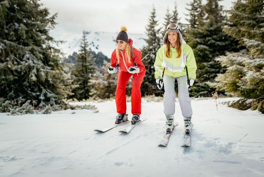 Beautiful young woman friends enjoying in ski vacations. They are skiing with smile.