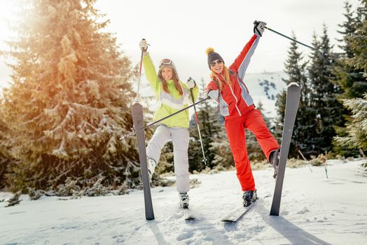 Beautiful young woman friends enjoying in ski vacations. They are having fun and looking at camera with smile.