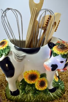 Distort cow with the hollow back and the kitchen utensils on a white bottom