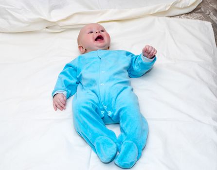 Four month old baby smiling while lying on the bed