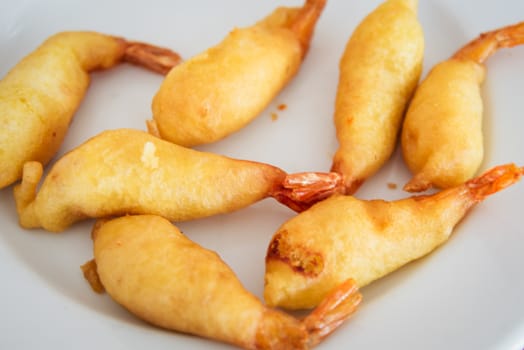 Fried shrimp tempura on a white plate .