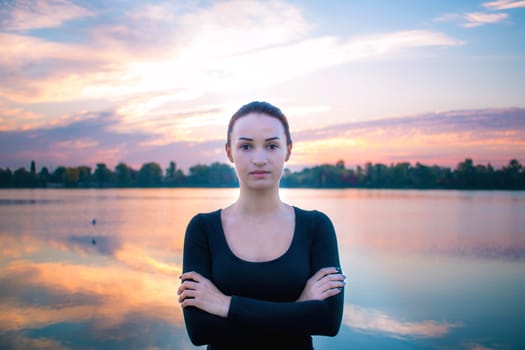 Young pretty woman portrait in early morning at colorful sunrise background