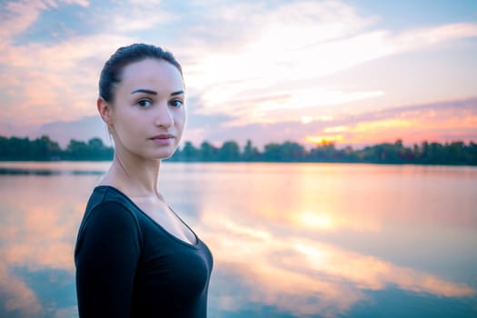 Young pretty woman portrait in early morning at colorful sunrise background