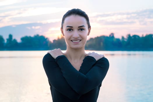 Young pretty woman portrait in early morning at colorful sunrise background