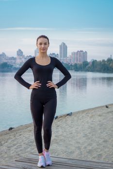Young fitness woman stands on pier preparing for training exercises workout at early morning sunrise time