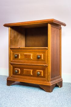 Wooden antique nightstand on the light background in the room