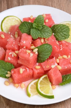 A refreshing salad of watermelon cubes with slices of lime, mint, peanuts, pine nuts