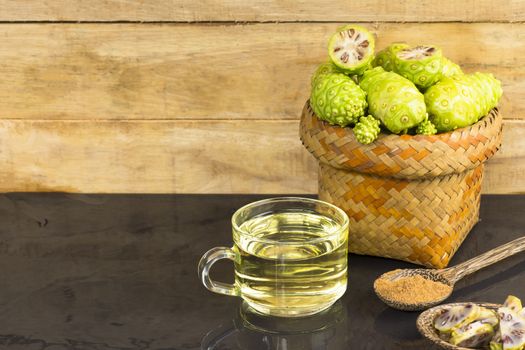 Noni fruit  and noni juice with noni powder on black table.Fruit for health and herb for health.