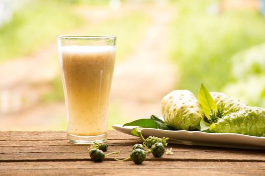 Noni and noni juice on wooden background.Juice for health or fruit for health or herb for health.Outdoor view1