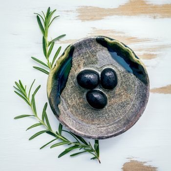 Bowl of extra virgin olive oil with rosemary. Sprigs of rosemary and olive oil set up on white shabby wooden background . Fresh branch of rosemary with bowl of olive oil with flat lay .