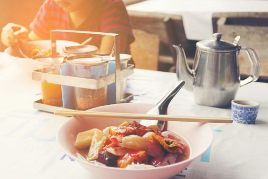 Roadside restaurant of Asia with Thai noodles and background of boy eating his noodle on table.11