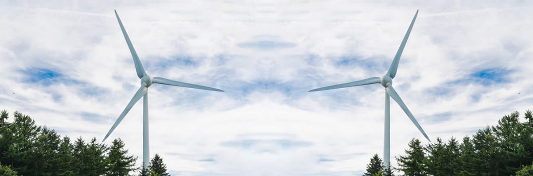 Two wind turbines under an overcast sky with light rays.