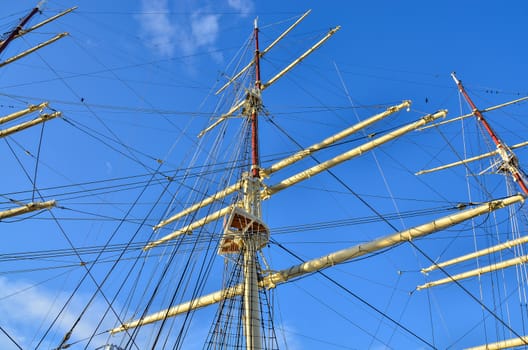 Crows nest, mast, and canvas sails can be seen in this closeup detail of an old time tall wooden sailing ship.