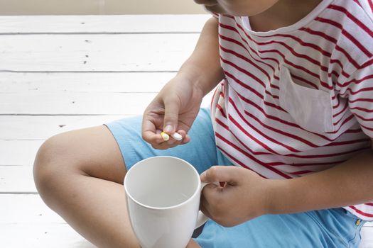 Sick child eating pills with wooden white background .Top view11