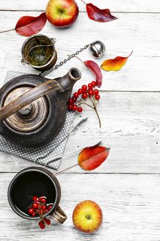 clay kettle with tea with berries on autumn background