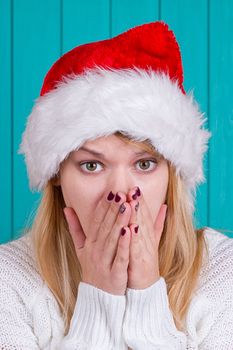 Christmas time. Young woman wearing santa claus hat red dress on blue background. Surprised face expression.