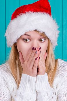 Christmas time. Young woman wearing santa claus hat red dress on blue background. Surprised face expression.