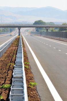 A vertical, image of an empty highway road and an overpass above it.