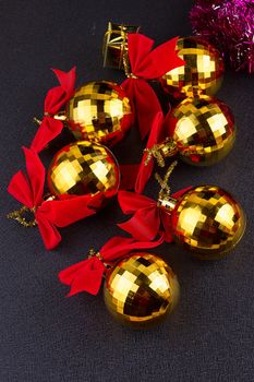 gold Christmas balls with red ribbons on a black background