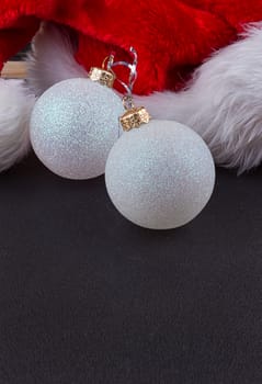 Christmas baubles and Santa hat, black background