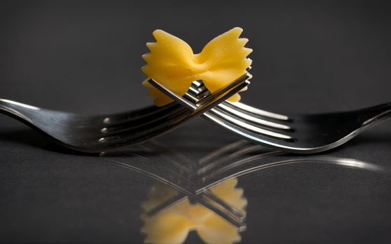 pasta farfalle on a fork on black background