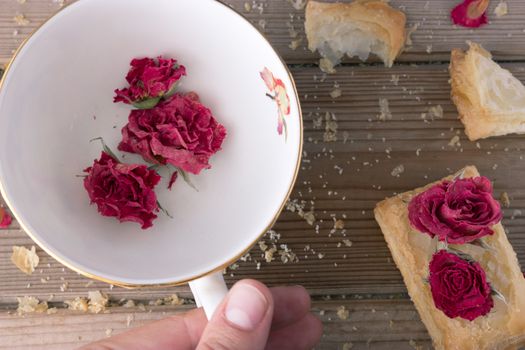 cookies and cup with dry roses and hand