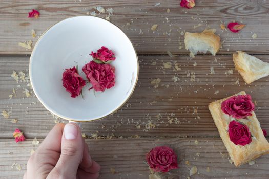 cookies and cup with dry roses and hand