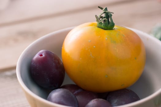 yellow tomato and black plum in a plate