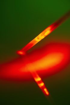 Red bright light source on the end of the probe in a plastic tube on a green background