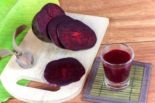 Fresh slices red beet root and beet root fruit juice in shot glass a wood background