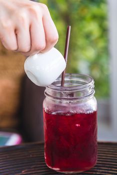 hand pouring syrup in berry juice jar