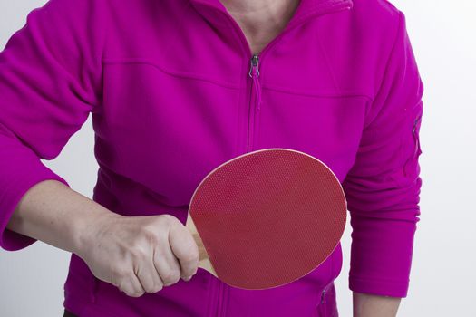 Active senior woman playing table tennis in front of white background