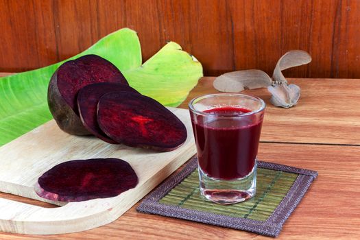 Fresh slices red beet root and beet root fruit juice in shot glass a wood background