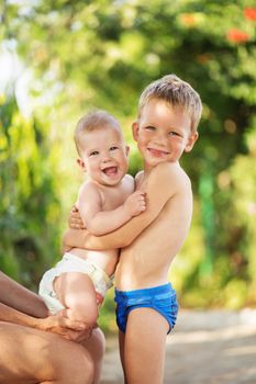 Little kids playing outdoors on hot summer day. Little boy holds on hands her baby sister