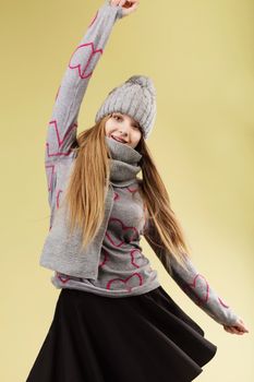 Cute teenage girl wearing gray woolen cap and scarf against yellow background