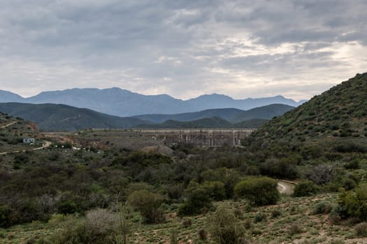 Dam wall at Calitzdorp, cloudy with mountains in the background.