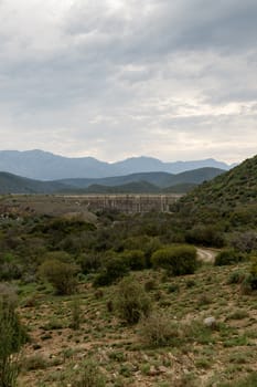 Portrait - Dam wall at Calitzdorp, cloudy with mountains in the background.